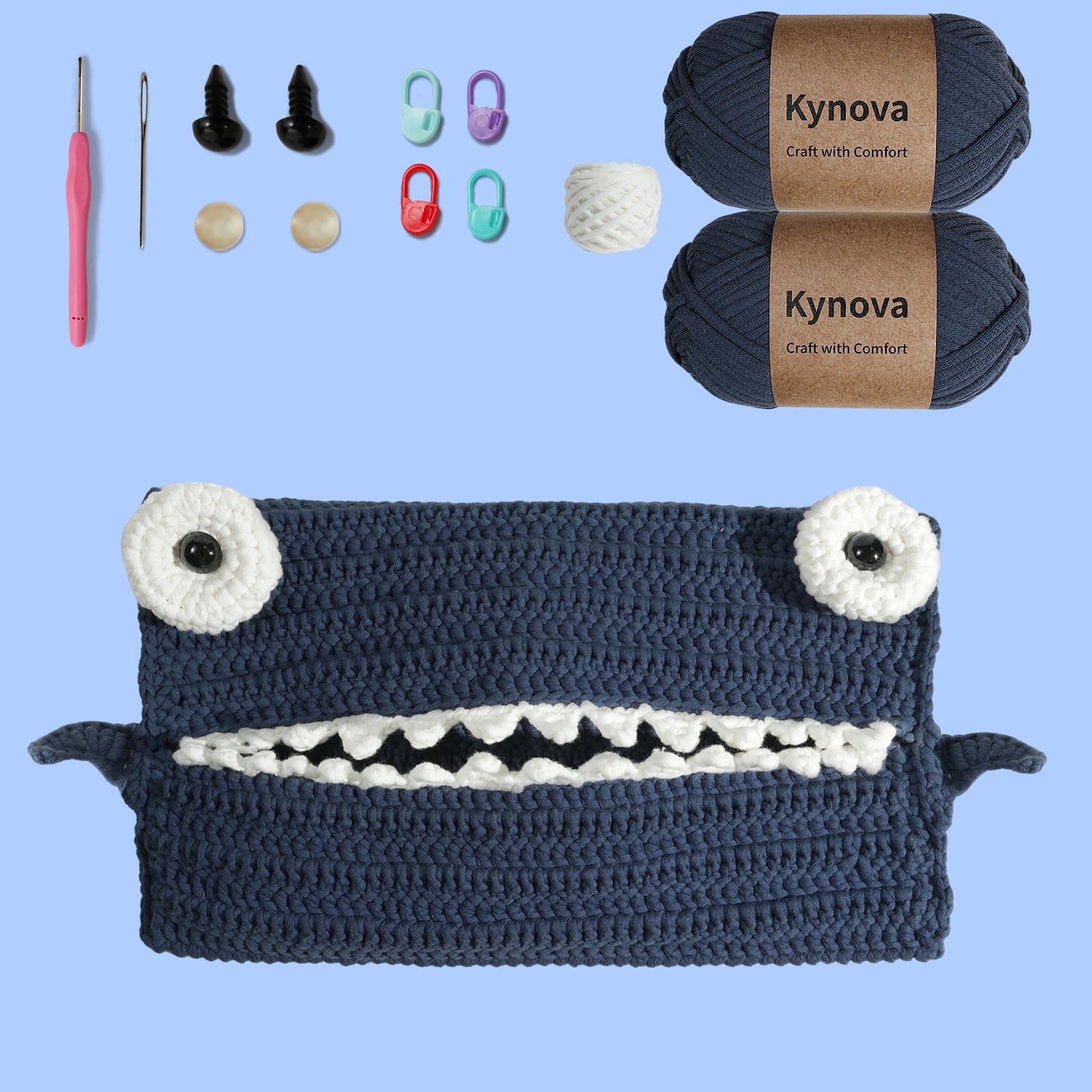 Crochet kit for making a shark-themed storage bag, including navy yarn, a crochet hook, buttons, a sewing needle, and a video tutorial.
