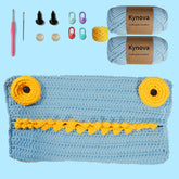 Crochet kit for a lizard-themed storage bag, including yarn in earthy tones, a crochet hook, buttons, a sewing needle, and other crafting materials.