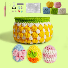 A crochet kit for Easter eggs and a basket, including colorful yarn, crochet hooks, and other crafting supplies arranged neatly on a light background. Crocheted eggs and a woven basket are also visible.