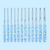 A set of 12 crochet hooks with floral patterned handles in various sizes, laid out in a row against a light blue background.