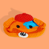 A crochet eyeglass case designed to resemble a puppy with a red hat, black eyes, and a blue collar.