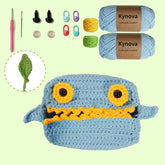 Crochet kit with a completed blue and yellow creature, Kynova yarn, hooks, and other tools on a light green background.