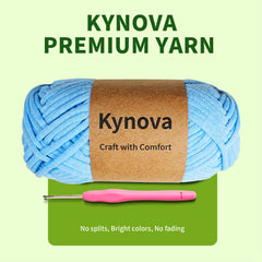 Blue yarn ball with Kynova label and pink crochet hook on green background