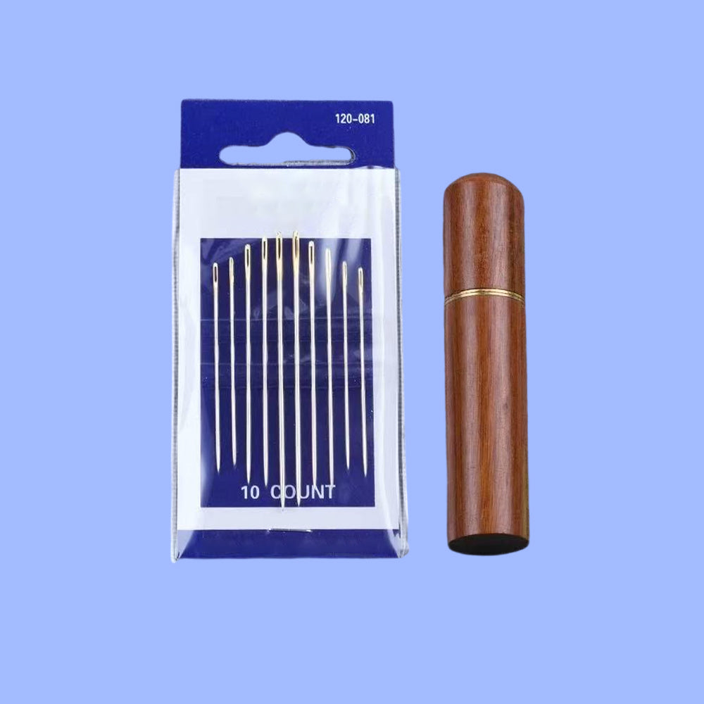A 10-piece large-eye sewing needle set displayed in its packaging, which includes a blue card with needles arranged neatly on it, alongside a brown wooden storage box.