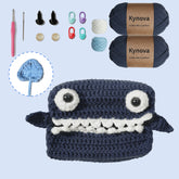 Crocheted shark toy with Kynova yarn and crochet tools on a light blue background